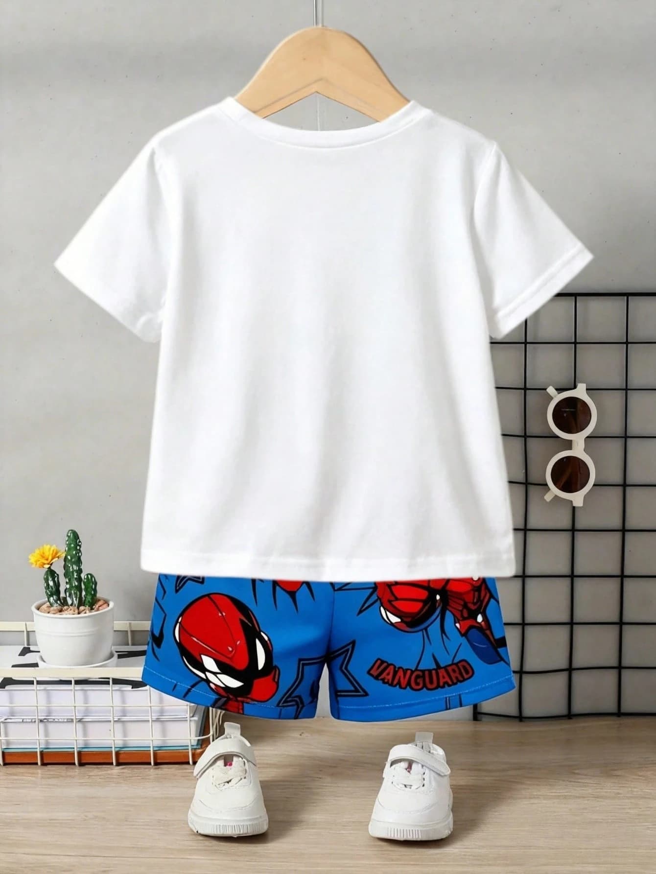 Back view of the kids' outfit on a hanger — a plain white T-shirt with the printed blue superhero shorts below.